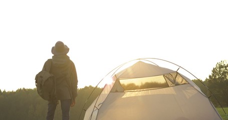 Fototapeta na wymiar girl sets up tent on grass