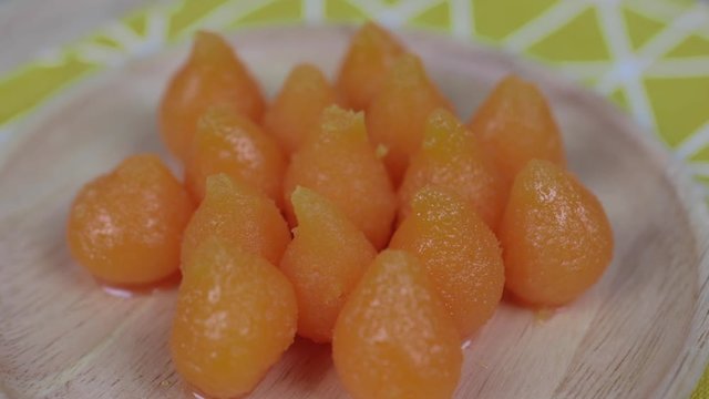 A kind of Thai Sweetmeats - Thong Yot on a wooden plate . Golden Drops , Eggdrop Sweet , Golden Balls , Thai famous desserts , rotating on a wooden plate