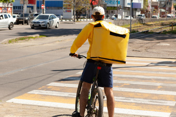 Delivery man of takeaway on bike with isothermal food case box driving fast. Express food delivery service from cafes and restaurants.