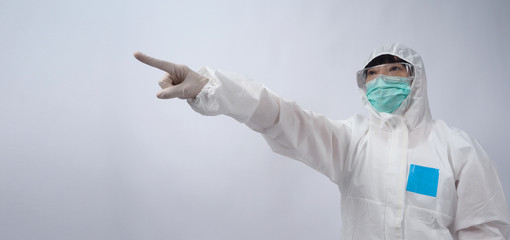Doctor in PPE suit or Personal Protection Equipment point out to copy space and wearing white color medical rubber gloves and clear goggles glasses and green N95 mask to protect pandemic virus