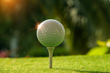 Golf ball on tee in the evening golf course with sunshine.