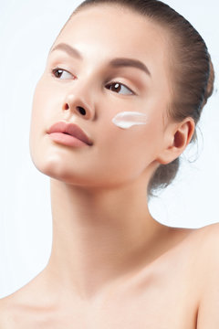 Young beautiful woman applies cream on clean perfect skin