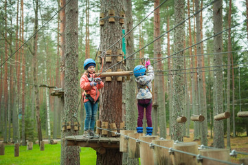 a girl walks on a tightrope to a rope park, a climbing center. Hiking in the rope park, the girls are safe.