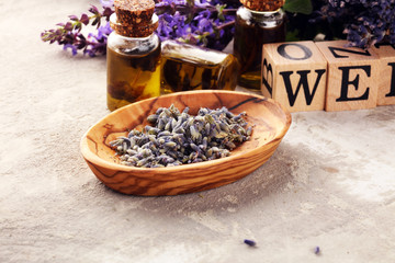 Obraz na płótnie Canvas lavender herbal oil and lavender flowers. bottle of lavender massage oil for aromatherapy treatment and wellness letters made of wood