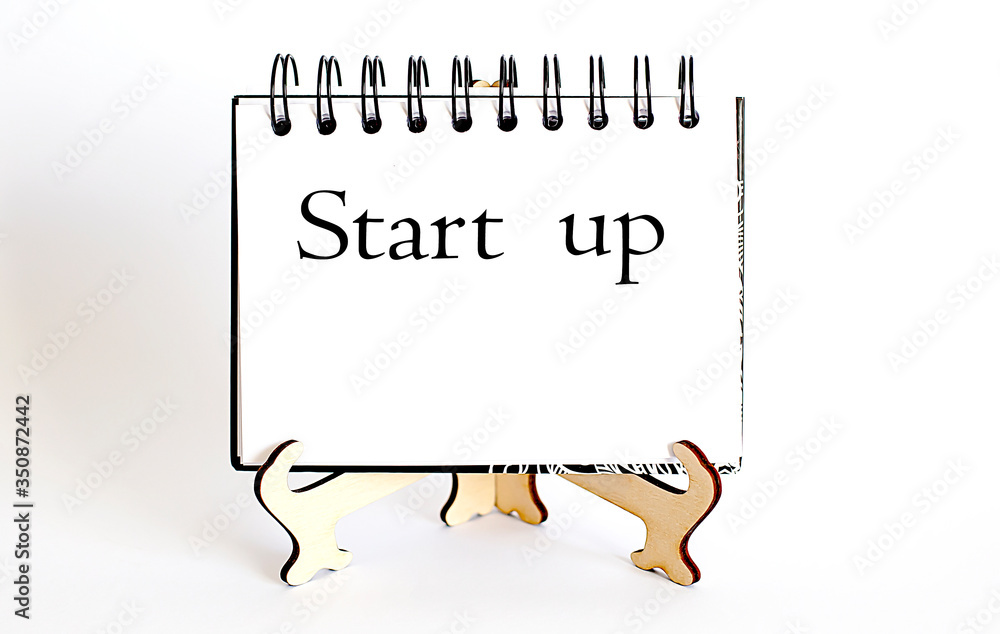 Poster desk with stationary and notebook with text start up.