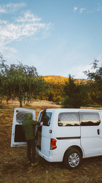 Hombre al amanecer en la monta&ntilde;a con furgoneta camper preparando el desayuno