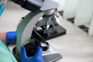 A microscope is on a white table in a hospital laboratory.