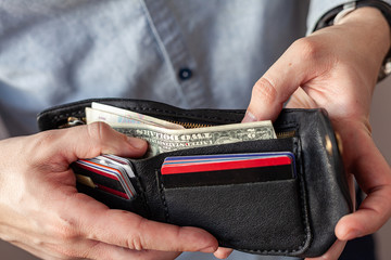 male hands hold a purse. A wallet with little money in it. The concept of poverty and bankruptcy