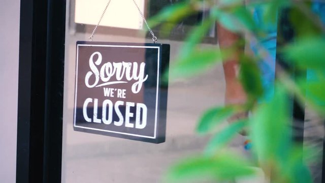 Sorry we're closed sign. grunge image hanging on a dirty glass door.	