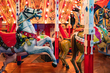 Carousels. Wooden horses spin around the post. Joy for children. Children's entertainment. The bright carousels are empty. Carousels are waiting for kids. Riding on wooden horses.