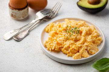 Fresh cooked scrambled eggs in a plate on white background.