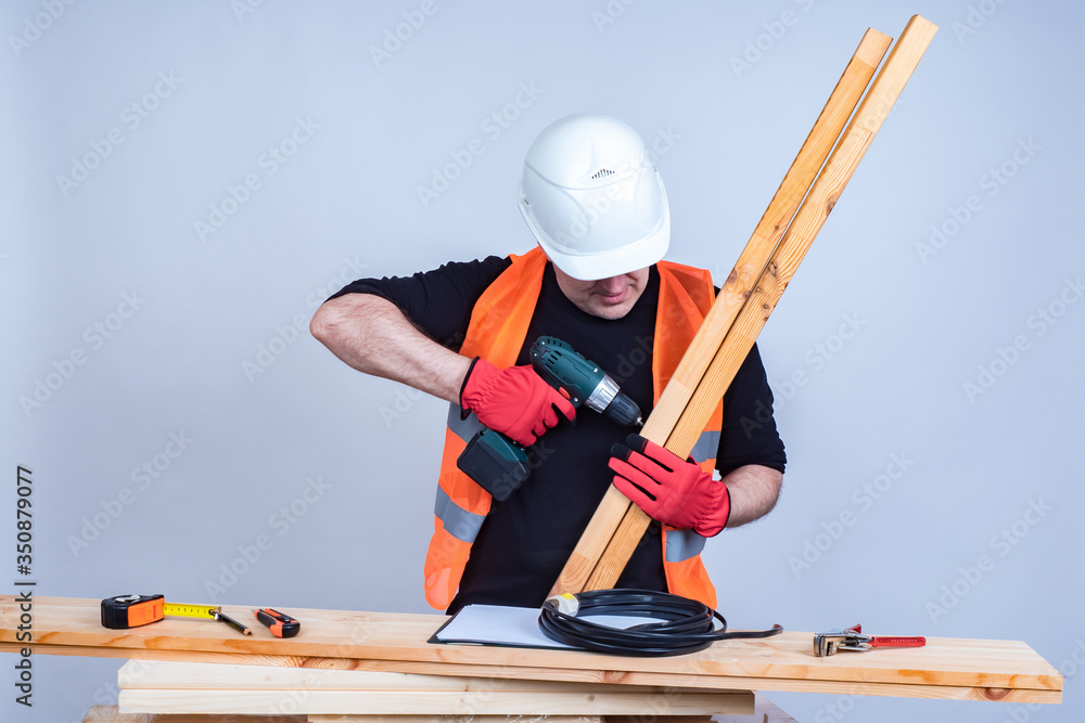 Poster a man works with a cordless screwdriver. carpenter with a tool i