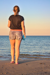 Mujer a la orilla del mar mirando el horizonte con la esperanza de terminar el confinamiento por el virus del COVID-19