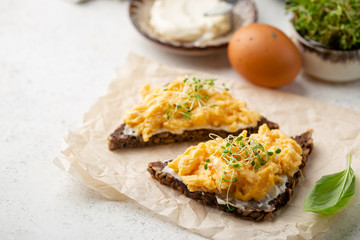 Scrambled egg sandwich with cream cheese on rye toast for breakfast on white background. Healthy breakfast or snack