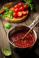 Classic homemade Italian tomato sauce with basil for pasta and pizza in the pan on wooden background.