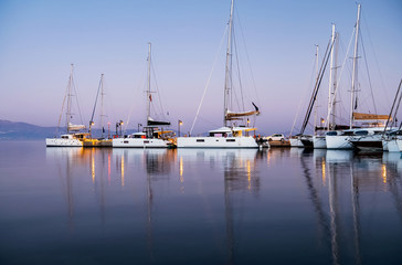 Fototapeta na wymiar Yachts in the harbor at dawn. Beautiful reflection. Nature background. Concept of silence, relax and tranquility. Luxury lifestyle.