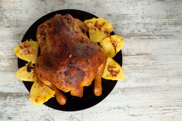 fried chicken with potatoes on a black plate on a white wooden background