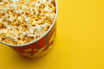 Popcorn in a bowl on yellow background, top view.