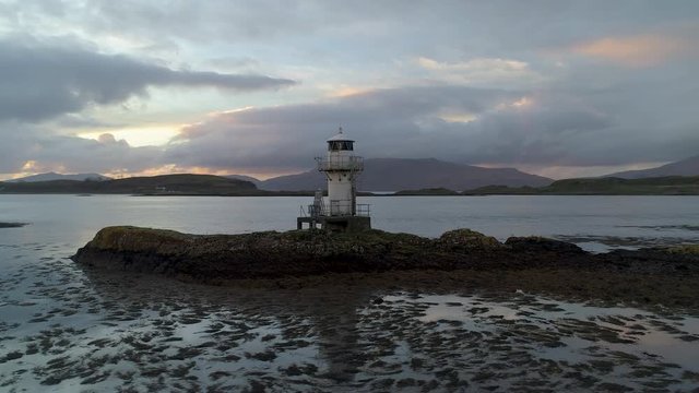 Beautiful isolated lighthouse surrounded by mountains and island overlooking huge expanse of water