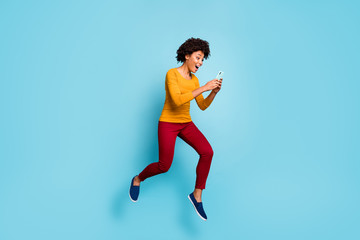 Fototapeta na wymiar Full length body size view of her she nice attractive positive glad cheerful cheery wavy-haired girl jumping running using cell having fun isolated on bright vivid shine vibrant blue color background