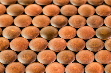 close-up background of many orange organic powder tablets laid tight in one layer on flat surface
