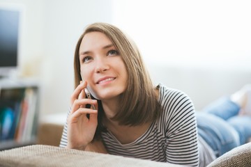 Beautiful young caucasian woman on  sofa using cell phone