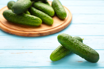 Fresh cucumbers on a wooden cutting board on blue wooden background