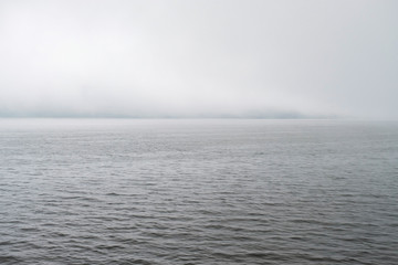 Clouds fog over mountain lake Beratan in Bali. The calm expanse of water under thick clouds