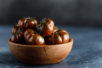 Obraz premium Fresh tomatoes in a plate on a dark background. Harvesting tomatoes.
