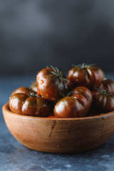 Fresh tomatoes in a plate on a dark background. Harvesting tomatoes.