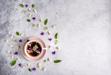 Obraz na płótnie Canvas Beautiful feminine pink cup with fresh wild flower tea and spiral floral decoration