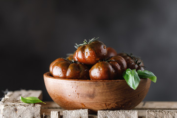 Fresh tomatoes in a plate on a dark background. Harvesting tomatoes.