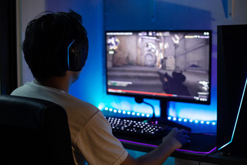 Back view of young gamer playing FPS video games at home © panuwat