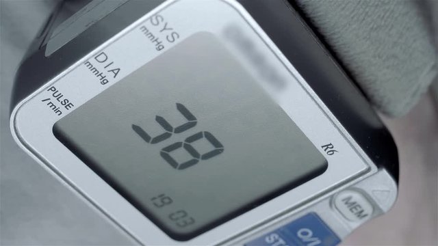 A wrist blood pressure monitor measures a person&rsquo;s vital signs and a pressure of 129 by 85 and a pulse of 82. Macro. Closeup. Shallow depth of field
