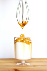 Dalgona coffee in glass on wooden table with cream on whisk. Creamy whipped trendy iced drink with coffee and milk. Food during self-isolation.