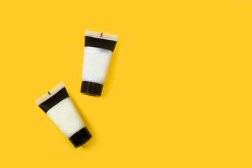 Tubos de crema para el cuidado del cuerpo y de la piel sobre un fondo amarillo brillante liso y...