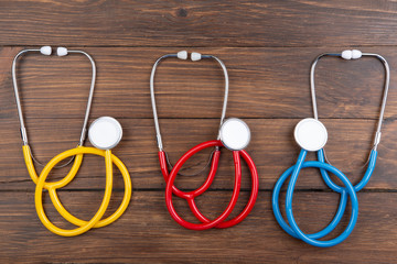 Workplace of a doctor. Color stethoscopes on wooden desk background