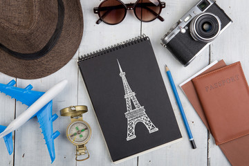 Travel to Paris concept - sketch of Eiffel tower, Airline tickets, passport, sunglasses and camera on wooden desk