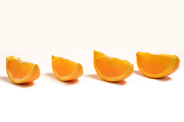 Four fresh orange segments placed in parallel with white background