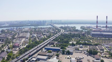 Obraz premium panorama with river and pipe factory on top shot of a modern industrial motor vehicle interchange with overpasses and bridges. part on reconstruction with speed limits to a minimum. aerial view 
