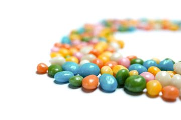 Obraz premium Sweet and bright assorted bean candies making placed in a half circle on white isolated background