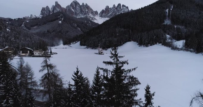 Fly through trees reveals church in Val Di Funes, Italy Dolomites