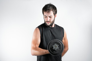 Fototapeta na wymiar Young and handsome man with a beard in fitness session, lifting weights or dumbbells, exercising the biceps muscle. On a white background.