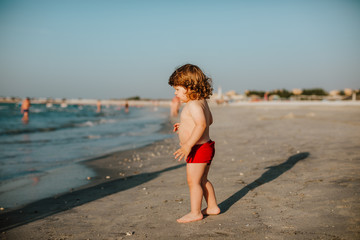 Toddler boy looking at the sea in Dubai in the summer
