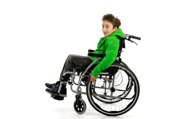 Little boy in wheelchair on white background , boy is sitting in a wheelchair on a white...