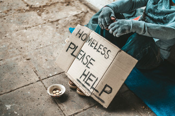 The beggars sat beside the street with a homeless message. Please help and work with food.
