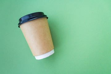 Coffee to go concept. Disposable craft cup with black plastic cover on a trendy grey background. Place for text. Flat lay style. Top view