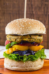 vegan meal, meatless hamburger, gluten free, made with different vegetables and proteins. Brown bread on gourmet hamburger, rustic background.