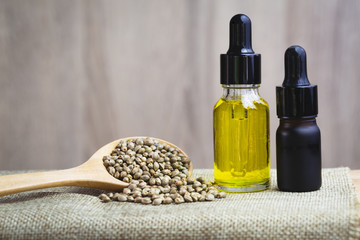 Glass bottles containing  hemp oil and hemp seeds in a wooden spoon,  drugs extracted CBD Cannabis Oil  of researchers or medical team. Herbal alternative medicine.