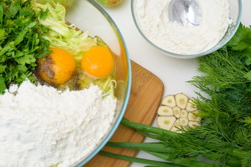 step-by-step recipe to cook pancakes of zucchini and greens on a light background. with the addition of eggs, flour, garlic, pepper. the view from the top